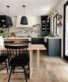 a kitchen with wooden floors and black cabinets is seen in this image from the dining room