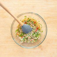 a wooden spoon is in a glass bowl filled with vegetables and sprinkles