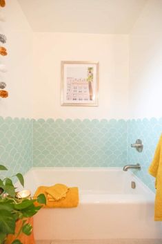 a bathroom with a bathtub, towel rack and potted plant in the corner