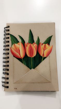 a drawing of three orange tulips in an envelope on a white table top