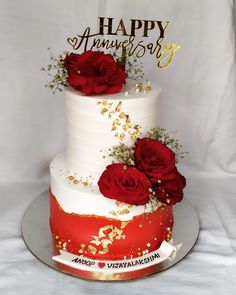 a three tiered cake with red roses and gold sprinkles