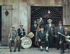 a group of men standing next to each other in front of a building with musical instruments