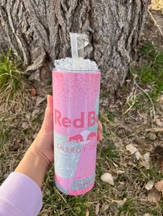 a person holding up a pink and silver drink in front of a tree with the words red blvd on it