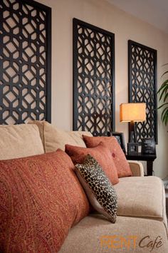 a living room with couches and pillows in front of three decorative wall hangings