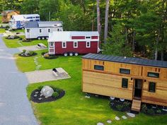 an aerial view of several tiny houses in the grass with trees and rocks around them