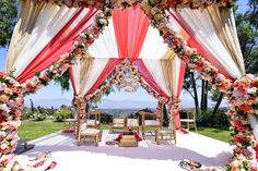 an outdoor wedding setup with pink and white draping, floral decorations, and chandelier