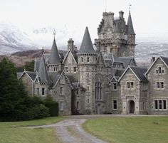 an old castle is shown in the middle of a grassy area with mountains in the background