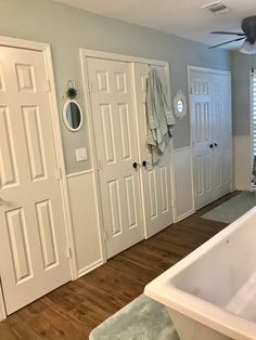 a bath tub sitting in the middle of a bathroom next to two doors and a window