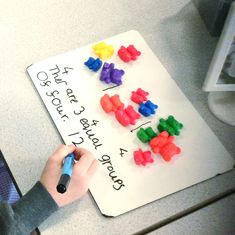 a child is writing on a white board with colored gummy bears attached to it