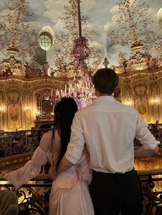 a man and woman standing in front of a chandelier