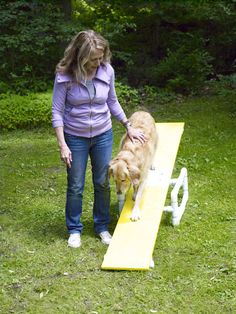 a woman standing next to a yellow bench with a dog on it