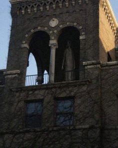 an old brick building with two statues on the balcony