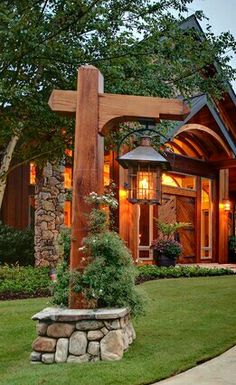 a large wooden cross sitting in the middle of a lush green yard next to a house