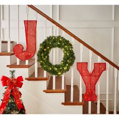 christmas decorations on the banisters and stairs are decorated with red mesh stockings that spell out joy