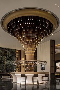 a bar with stools and lights hanging from the ceiling in a large room that has marble flooring