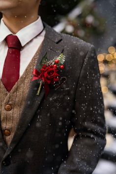 a man wearing a suit and tie with a red boutonniere