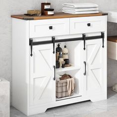 a white cabinet with two sliding doors and some towels on it's shelf next to a sink