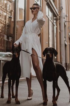 a woman is walking two dogs down the street