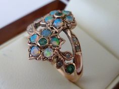 BEAUTIFUL ART NOUVEAU VINTAGE INSPIRED 9CT/9K SOLID ROSE GOLD EMERALD, OPAL & DIAMOND VINTAGE FLOWER RING This ABSOLUTELY lovely Vintage Inspired Art Nouveau floral ring has been crafted from 9ct Solid Gold. A round cut Natural Emerald Gemstone lies in the centre surrounded by petals with inset Natural Australian Opals. A highlight of this ring is the double flower featured face, diamond inset leaves and Emerald on each shoulder making this ring a gorgeous standout mastercrafted jewellery pi Luxury Green Opal Ring With Diamond, Gold Antique Ring, Diamond Ring Rose Gold, Flower Diamond Ring, Opal Diamond Ring, Vintage Inspired Art, Ring Flower, Floral Ring, Antique Ring