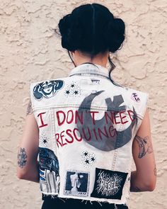 a woman with black hair wearing a denim vest that says i don't need rescuing