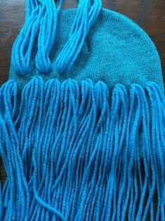 a close up of a blue bag on a wooden table with some tassels