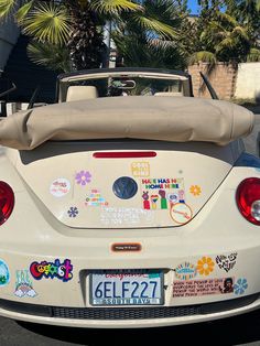 the back end of a white car with stickers all over it's hood