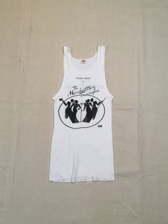 "1970s band tanktop shirt Hanes, cotton, white ribbed The Manhattan Transfer black print Atlantic Records symbol at lower right of image front/back image good vintage condition, light wear light stains, light cracking label size M, see below measures, lying flat, chest-12\" unstretched to 19\" stretched length-26\"" Fitted Sleeveless Cotton T-shirt, Fitted Cotton Vest For Streetwear, Vintage Tank T-shirt For Summer, Fitted Cotton Crew Neck Vest, Vintage Tank Top For Spring Streetwear, Fitted Sleeveless Graphic Print T-shirt, White Fitted Cotton Vest, Fitted Cotton Muscle Tee With Graphic Print, Fitted White Cotton Muscle Tee