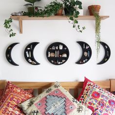 three moon shaped shelves are mounted on the wall above a bed with pillows and plants