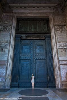 a woman standing in front of a large blue door