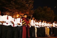 a group of people standing next to each other in front of some trees at night