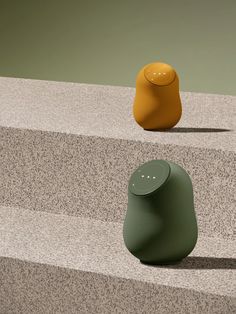 two different colored speakers sitting on top of cement steps next to each other in front of an orange and green object