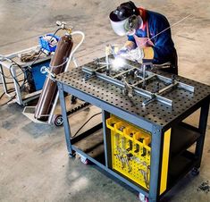 a man welding something on top of a metal table