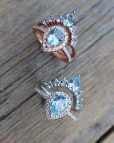 three different types of rings on a wooden surface with diamonds and blue topazs