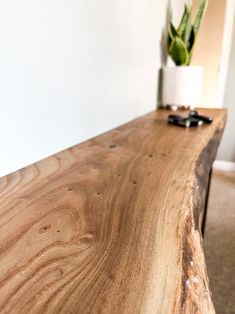 a close up of a wooden table with a plant in the corner on top of it