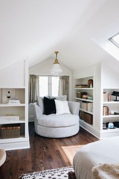 a bedroom with white furniture and bookshelves on the walls, along with a large round chair