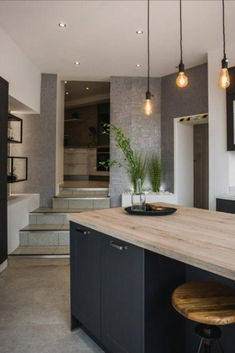 a kitchen with an island counter and stools in front of the sink, lights hanging from the ceiling