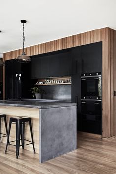 a kitchen with black cabinets and stools next to an island in the middle of it