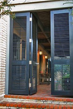 an open patio door with shutters on the outside and brick steps leading up to it