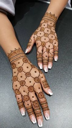 two hands with henna designs on them, one is white and the other is brown