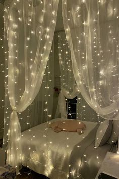 a bed with white curtains and lights on it