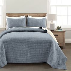 a bed in a bedroom with blue and white bedspread on top of it