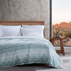 a bed in a bedroom with a view of the desert and mountains out the window