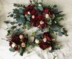 two bouquets of red and pink flowers on a white surface with greenery around them