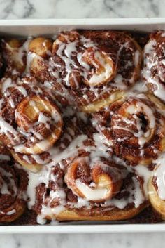 cinnamon rolls with icing in a white baking dish