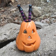 an orange jack o lantern with two black legs sticking out of it's mouth