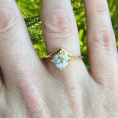 a woman's hand with a ring on it that has a blue stone in the middle