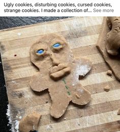 a wooden cutting board topped with cookies cut in half to look like a man's face