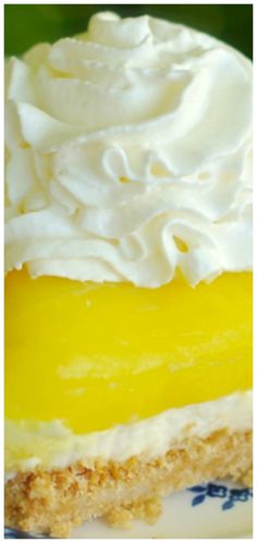 a piece of lemon pie with whipped cream on top is sitting on a blue and white plate