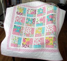 a pink and blue quilt sitting on top of a wooden chair next to a book shelf