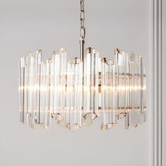 a chandelier hanging from the ceiling with clear glass tubes and lights attached to it